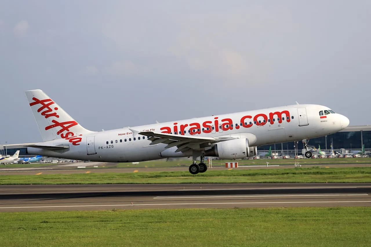 AirAsia Airbus A320-216 jet airliner takes off from runway on a clear day at an airport.