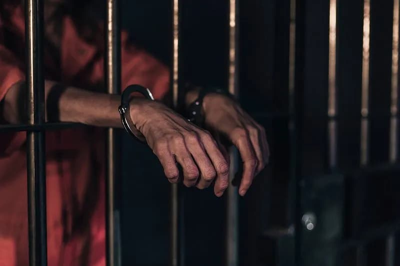 Handcuffed-hands on prison bars.